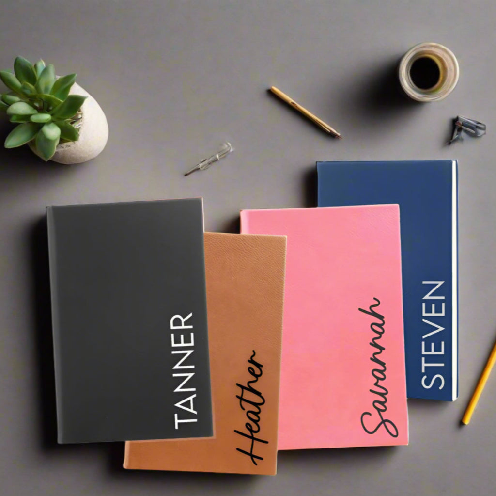Five notebooks in different colors with names printed on them against a white background